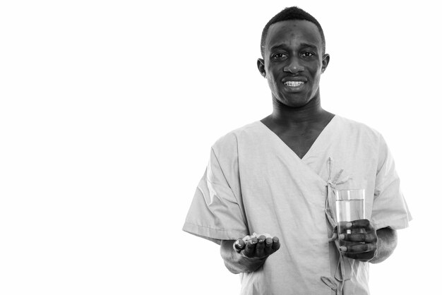 Paciente jovem africano negro feliz sorrindo enquanto segura comprimidos de vitaminas e um copo de água