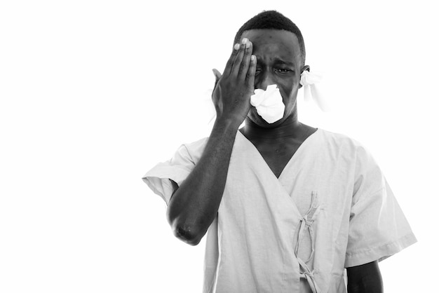 Paciente joven africano negro con dolor de cabeza y aspecto enfermo con tejidos en los oídos y la nariz