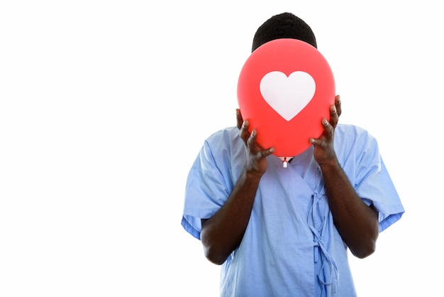 Paciente joven africano negro que oculta la cara detrás de un globo de corazón