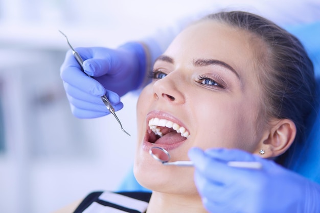Paciente joven con la boca abierta examinando la inspección dental en el consultorio del dentista