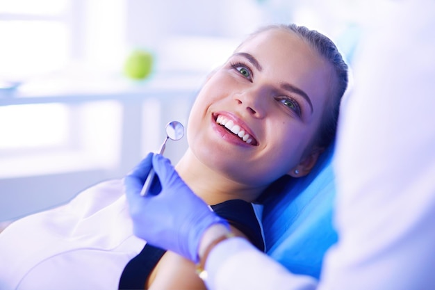 Paciente joven con una bonita sonrisa examinando la inspección dental en el consultorio del dentista