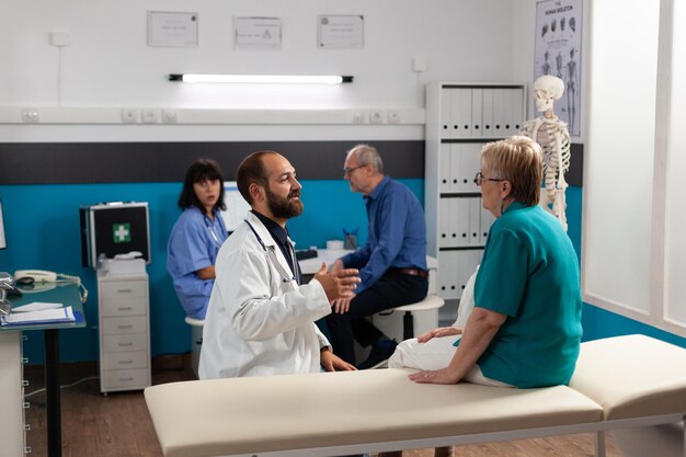 Paciente con lesión física hablando con el médico sobre la recuperación y el remedio para la atención médica. Médico explicando el método de estiramiento a la mujer mayor para el diagnóstico y tratamiento quiropráctico