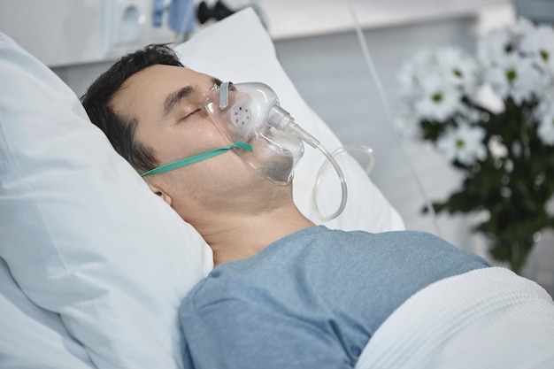 Paciente con máscara de oxígeno acostado en la sala del hospital