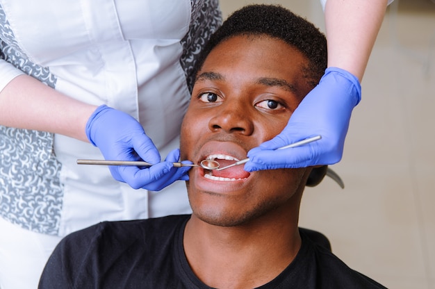 Paciente masculino africano recibiendo tratamiento dental en clínica dental