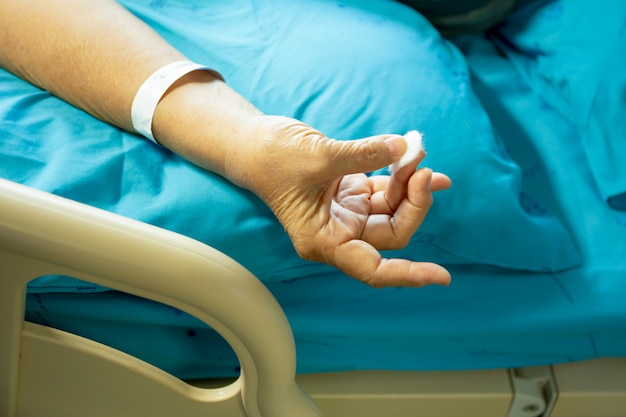 Paciente mayor con algodón que detiene la hemorragia sanguínea de un dedo.