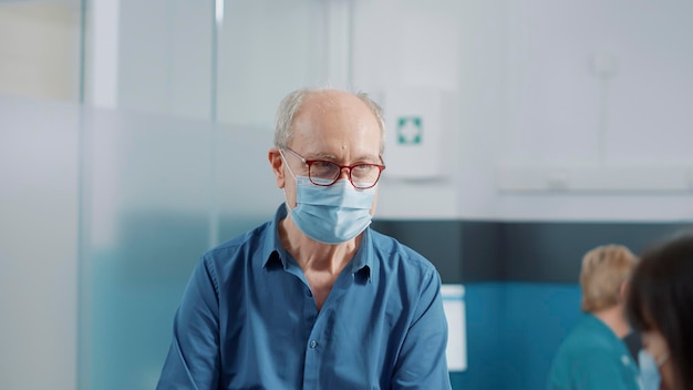 Paciente mayor hablando con un asistente médico sobre el servicio de recuperación durante la pandemia del coronavirus. Anciano y enfermera conversando en el examen de consulta de atención médica en el gabinete.