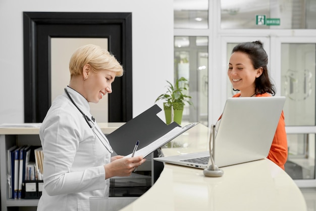 Paciente y médico con carpeta en recepción.