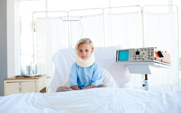 Foto paciente molesto con un cuello ortopédico sentado en una cama de hospital