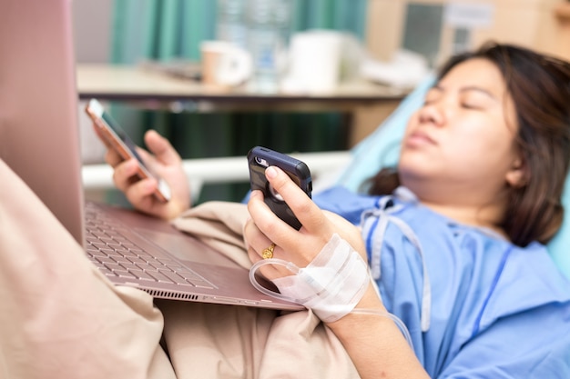 Paciente de la mujer de Asia que trabaja con el ordenador portátil durante en hospital