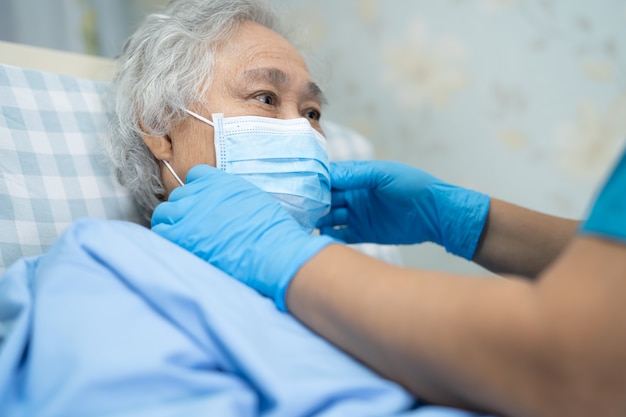Paciente mujer asiática mayor con rostro para proteger el coronavirus Covid-19.