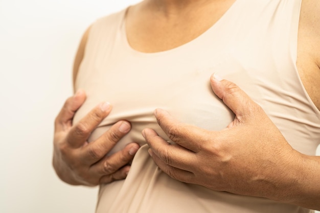 Paciente mujer asiática revisando y preocupando su mama Autoexamen de mama o símbolo BES del Día Mundial del Cáncer de Mama