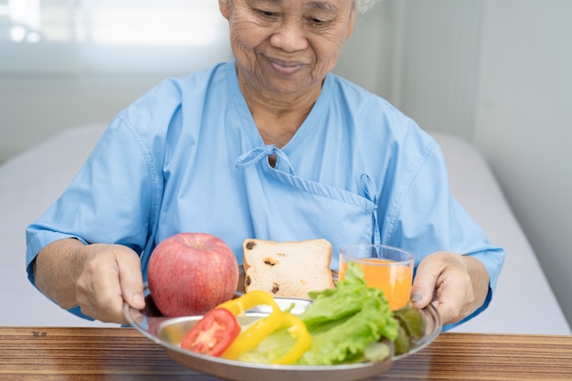 Paciente mujer mayor asiática que come el desayuno comida sana vegetal