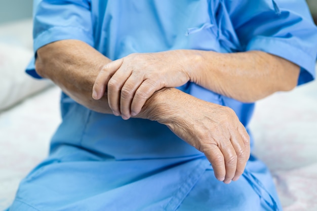 Paciente mujer mayor asiática siente dolor en el brazo en el hospital.