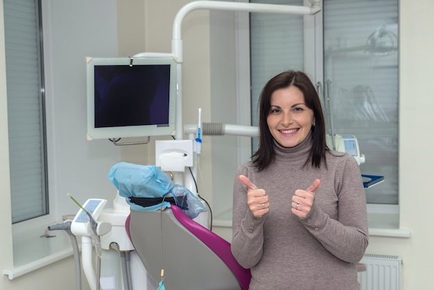 Paciente mujer sonriente en odontología después de procedimientos estomatológicos