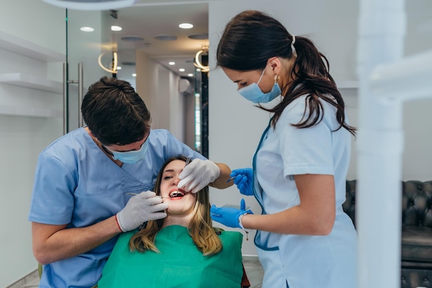 Paciente mulher na clínica odontológica sendo examinada por um dentista masculino