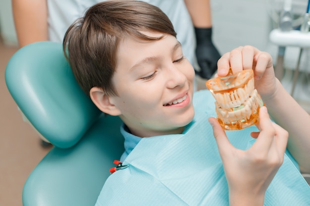Paciente na cadeira odontológica rapaz adolescente fazendo tratamento odontológico no consultório do dentista