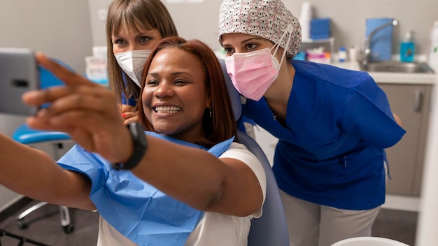 Una paciente negra se toma una selfie con dos dentistas en la clínica dental