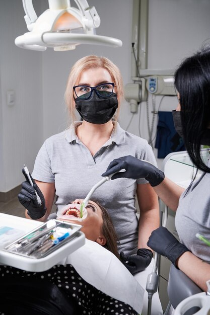 Foto paciente no consultório do dentista médico com seu assistente trabalhando