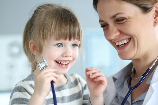 Paciente pequeno bonito de sorriso que interage com o doutor fêmea