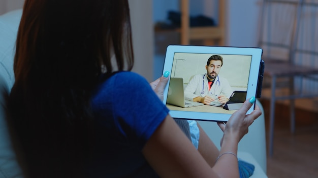 Foto paciente remoto con tableta con videoconferencia con el médico.