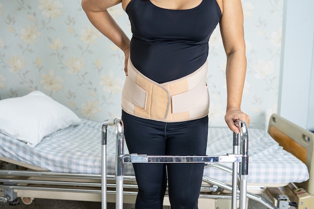 Paciente senhora asiática usando cinto de suporte de dor nas costas.