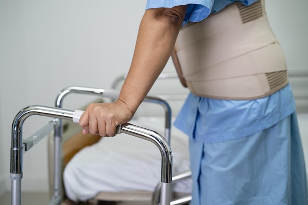 Foto paciente senhora asiática usando cinto de suporte para dor nas costas para ortopedia lombar com andador