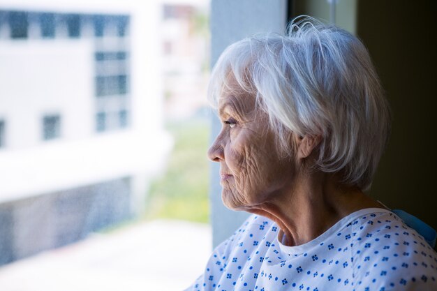 Paciente senior pensativo mirando por la ventana