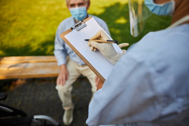 Foto paciente sentado no banco enquanto o médico escreve notas
