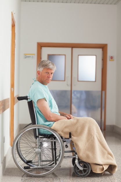 Paciente sentado en una silla de ruedas con una manta