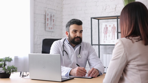 Paciente de sexo femenino que visita al médico de familia masculino en el consultorio médico para obtener el resultado del diagnóstico en rayos X