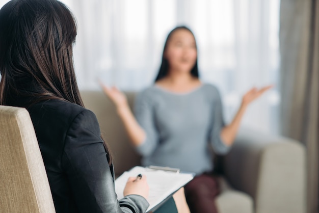 Foto paciente de sexo femenino sentado en el sofá al psicoterapeuta