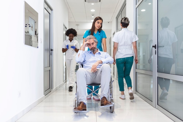 Paciente en silla de ruedas con doctora profesional y personal especialista en enfermería en el pasillo del hospital