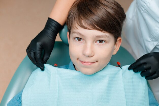 Paciente en el sillón dental Muchacho adolescente con tratamiento dental en la oficina de dentistas