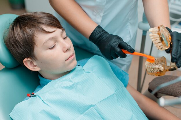 Paciente en el sillón dental Muchacho adolescente con tratamiento dental en la oficina de dentistas