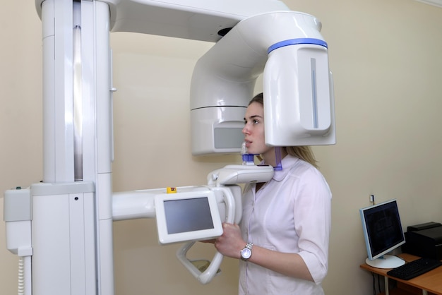 Paciente en el sistema de rayos X panorámicos y cefalométricos de un dentista. Chica hace una radiografía de sus dientes