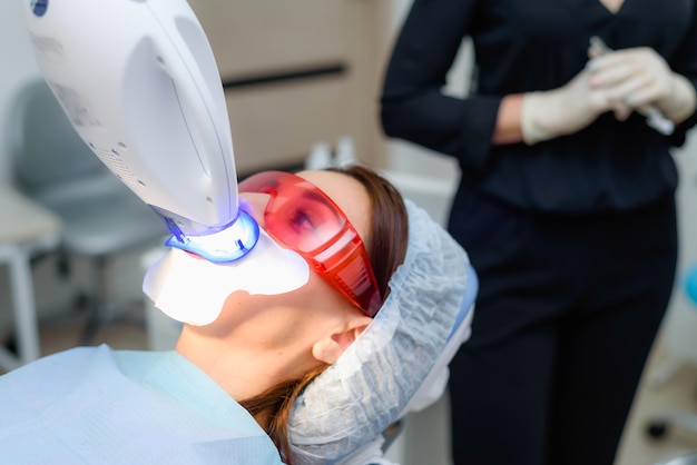 El paciente se somete a un procedimiento de blanqueamiento dental con una lámpara ultravioleta.