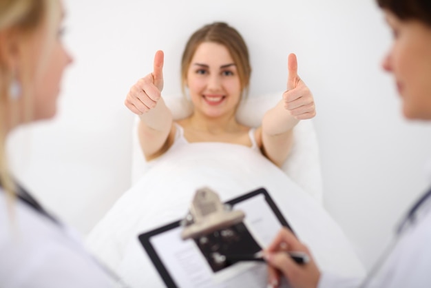 El paciente sonriente feliz muestra los pulgares para arriba en el hospital.