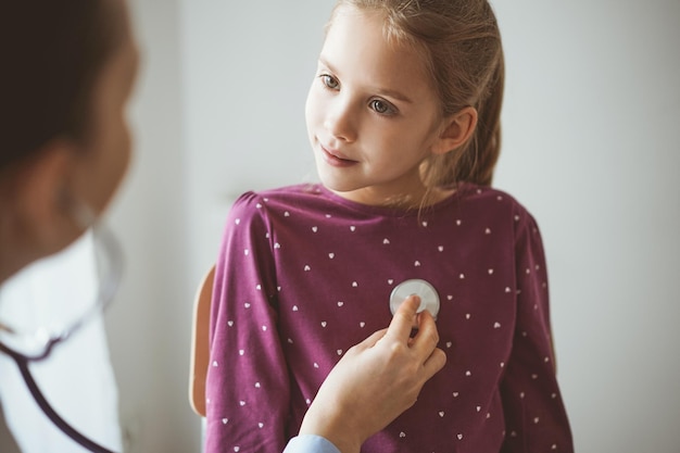 Paciente sonriente feliz de la niña del niño en la inspección médica habitual. Médico y paciente infantil en casa. Medicina, conceptos sanitarios