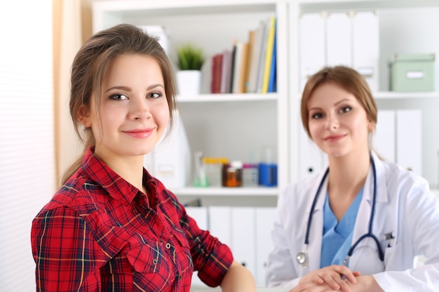 Paciente sorridente do sexo feminino sentado no consultório do médico. Assistência do terapeuta, consulta de consulta e conceito de estilo de vida saudável