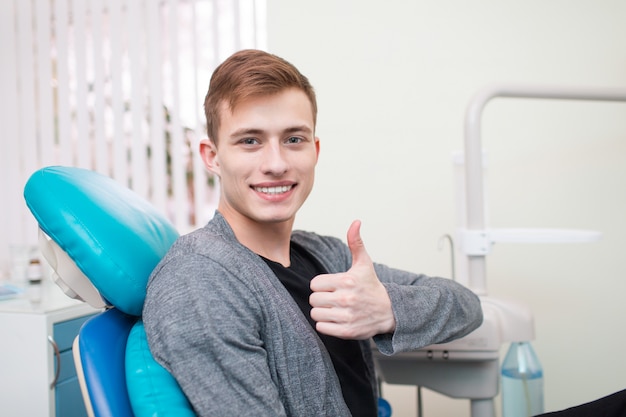 Paciente sorrindo e polegares para cima no dentista