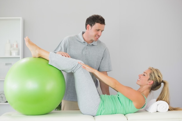 Paciente sosteniendo la pelota de ejercicios con las piernas