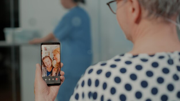 Paciente usando tecnologia moderna para falar com parentes na enfermaria do hospital. Velho doente fazendo videochamada no smartphone para conversar com a família sobre o andamento do tratamento e saúde