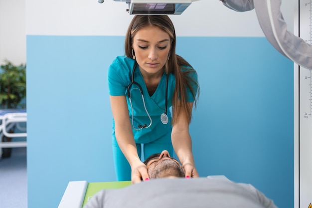 Paciente varón acostado en la cama mientras la enfermera ajusta la máquina de rayos X moderna para escanear su pecho en busca de lesiones y fracturas