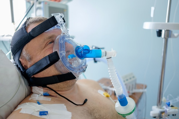 Foto paciente varón blanco realiza terapia de cpap con máscara de cpap en el departamento de cuidados intensivos.