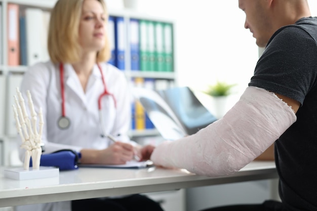 Paciente con yeso en el brazo roto consulta al médico en el hospital