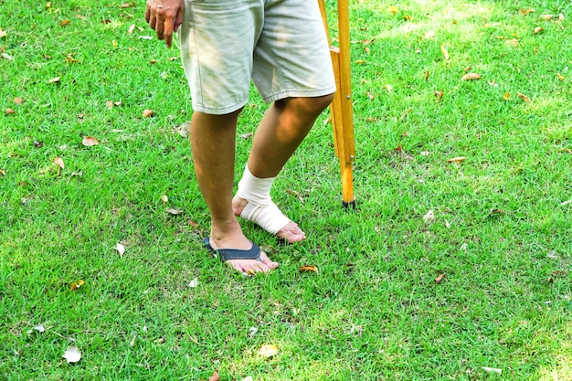 Pacientes com lesões no tornozelo com bandagens e suporte de tornozelo e usam muletas para se apoiar no gramado