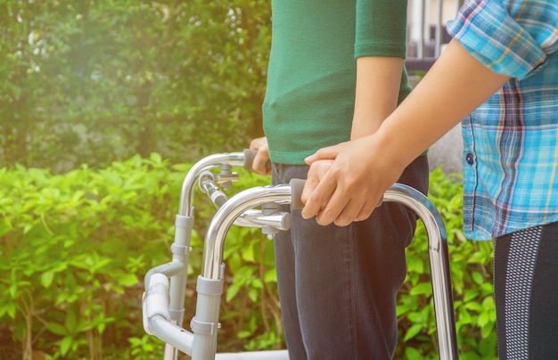 Pacientes do sexo feminino estão caminhando com Walker, com fisioterapeuta ajudando e aconselhando.