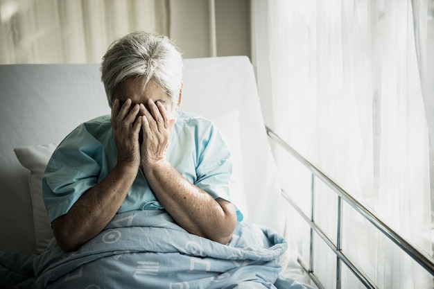 Foto pacientes de edad avanzada que se sientan en cama esperando que los familiares visiten con soledad.