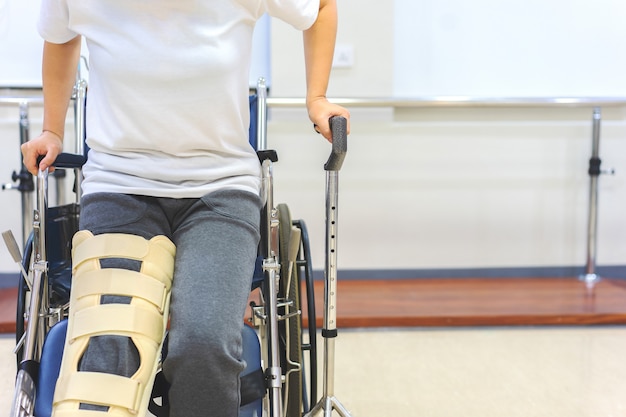 Foto las pacientes femeninas usan dispositivos de soporte de rodilla para reducir el movimiento al levantarse de la silla de ruedas.