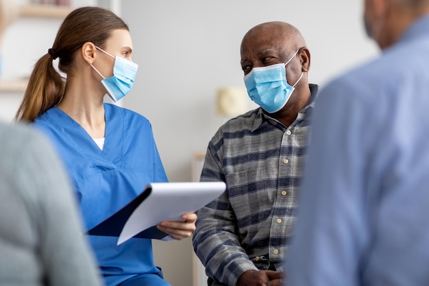 Pacientes mayores con mascarillas que conversan con la enfermera